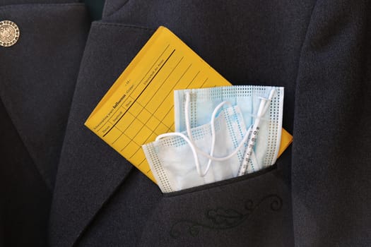 Everyday life and Corona vaccination. A vaccination card, protective masks and a vaccination syringe are in a jacket pocket