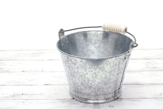 Empty metal bucket on white grunge wooden table