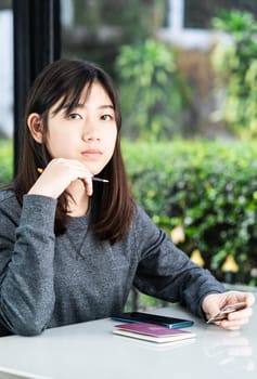Young woman sitting sholding credit card and passport on deck in home office