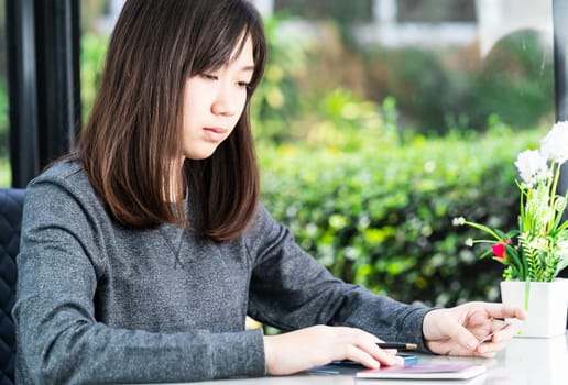 Young woman sitting sholding credit card and passport on deck in home office