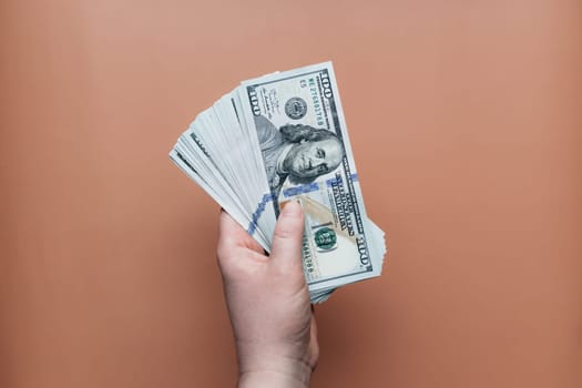Bundle of dollars in hand on beige background. High quality photo