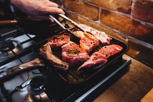 Hand turns steak with tongs during preparation on the grill pan with seasonings. High quality photo