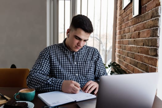 Man working at the laptop with a cup of coffee at home. Blurred background. High quality photo