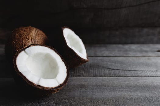 Broken coconuts on gray wooden background. White coconut pulp. High quality photo