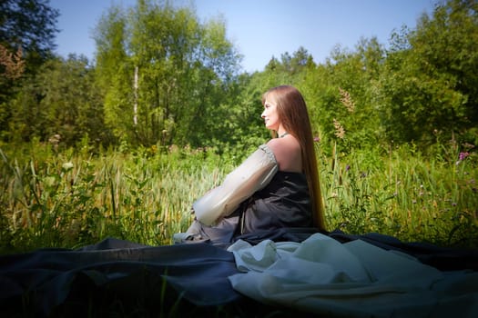 Beautiful dryad or fairy with gorgeous long hair in nature. Environmental friendliness, caring for nature. Adult mature woman 40-60 in Photo shoot