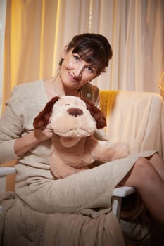 A middle-aged woman relaxes in her cozy apartment, embracing a plush dog during a peaceful evening at home.