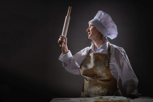 An elderly woman joyfully poses with a rolling pin, surrounded by flour in a playful kitchen setting, celebrating her love for cooking.
