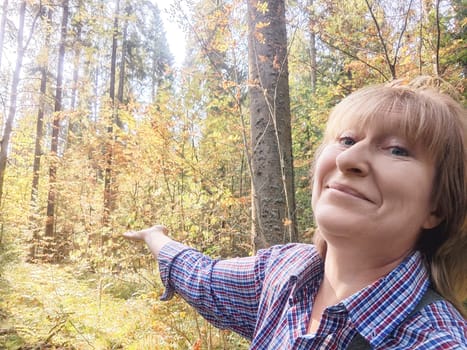 Blonde woman makes funny faces and points out scenery while exploring a colorful forest on her travel journey.