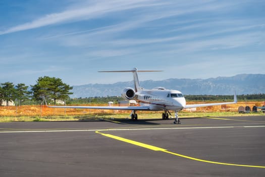 Small airplane parked on airport. Use of private jets to avoid coronavirus risk and restrictions. Dinaric Alps mountains in background, Zadar, Croatia