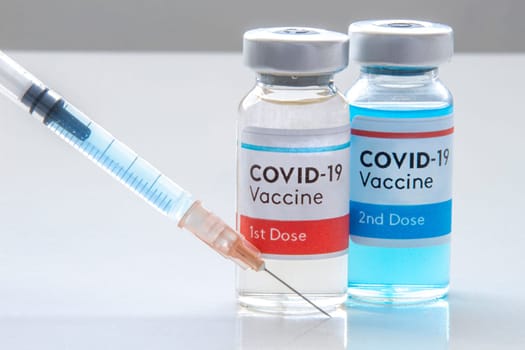 Calgary, Alberta, Canada. Nov. 27, 2020. A Moderna 1st dosis and a 2nd dosis of covid-19 vaccine on a vial bottle and injection Syringe on a white table