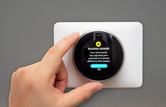 Calgary, Alberta, Canada. Feb 11, 2021. A Person setting up a Nest Thermostat to seasonal savings during the winter.