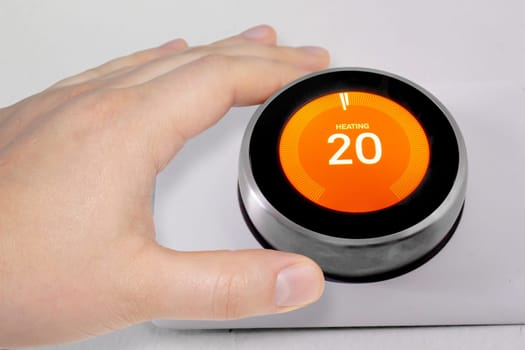 A person adjusting the temperature on a smart thermostat during winter