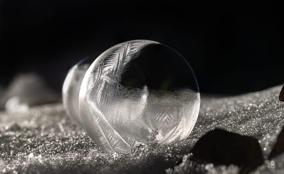 Detail shot of a frozen soap bubble on snow-covered ground against a black background at night