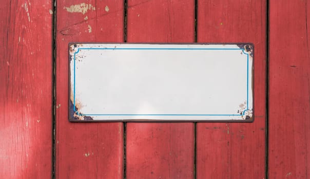 Empty tin sign in front of a wooden wall