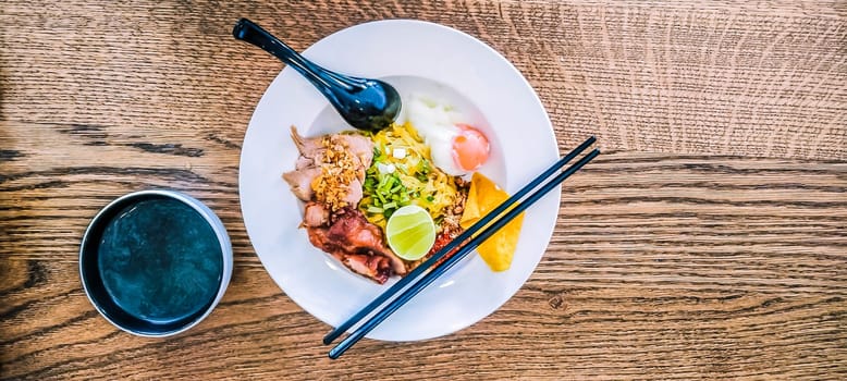 Miso Soup with Asian noodles with egg in bowl on wooden table background  with chopsticks and spoon