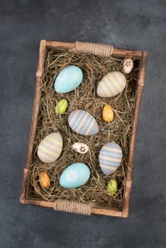 Colored easter eggs in a basket with hay, empty copy space for text