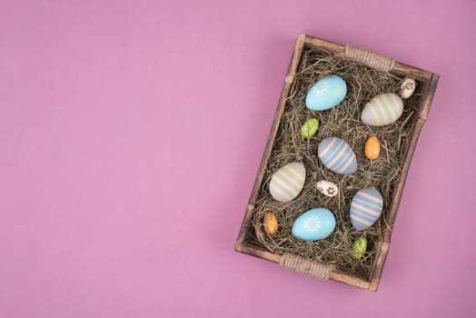 Colored easter eggs in a basket with hay, empty copy space for text