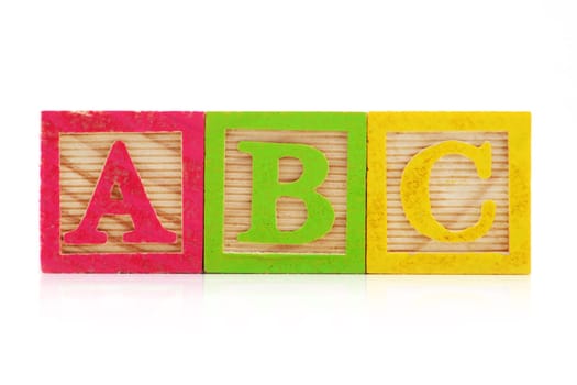 A front view of A B C wood blocks on white background with reflection.