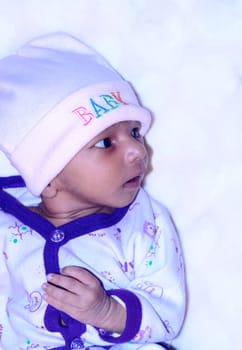 Closeup beautiful portrait of cute Indian newborn baby boy in winter clothing looking sideways feel curious and posing wonder. Sweet infant toddler isolated on white background. Copy space for text.