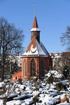 The historic Johanniskirche from the 13th century in the St.Johannis district of Nuremberg in the Johannisfriedhof. The graves are covered with snow.