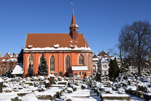 The historic Johanniskirche in the St.Johannis district from the 13th century in Nuremberg in the Johannisfriedhof. The graves are covered with snow.