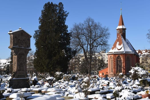 The historic Johanniskirche from the 13th century in the St.Johannis district of Nuremberg with Adam Kraft's first station of the cross in the Johannisfriedhof. The graves are covered with snow.