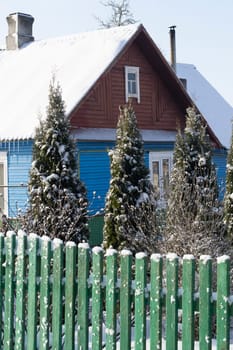 Wooden rural house with carved windows in winter. Snow, snowfall in countryside. Cold season in Belarus