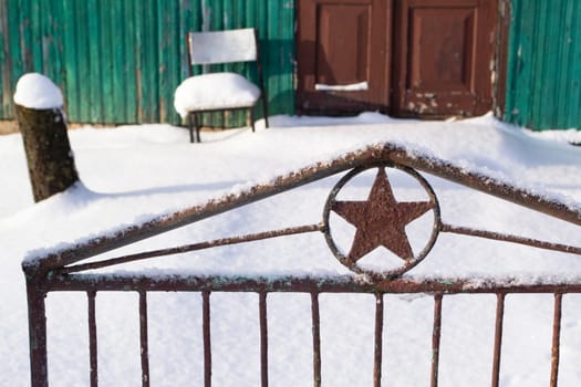 Soviet five finger star on a fence door background an old wooden fence, winter time