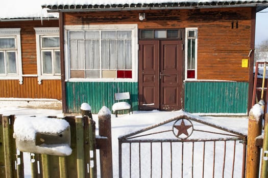 Facade of a traditional belarussian village old wooden house in winter with fence