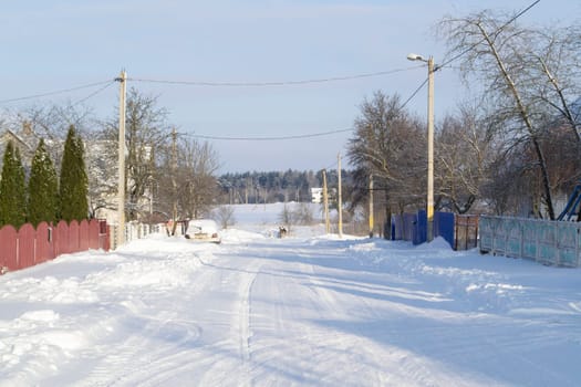 Winter snowy village from road view. Rural landscape in Belarus