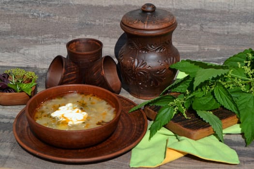 Soup of sorrel and nettles on the rustic table, springtime