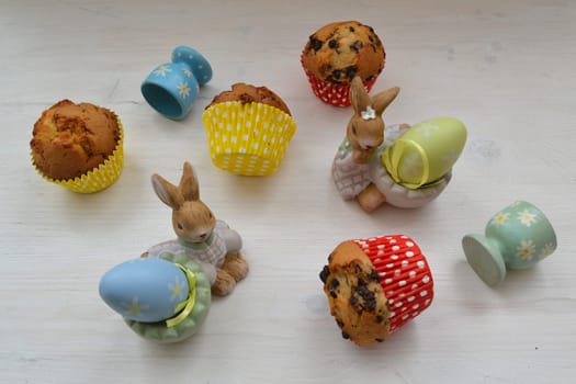 Easter cookies muffins with colorful eggs on white wooden background flat lay