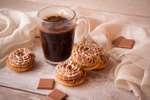 Cup of tasty coffee with tasty cookies or biscuits and chocolate, on wooden table