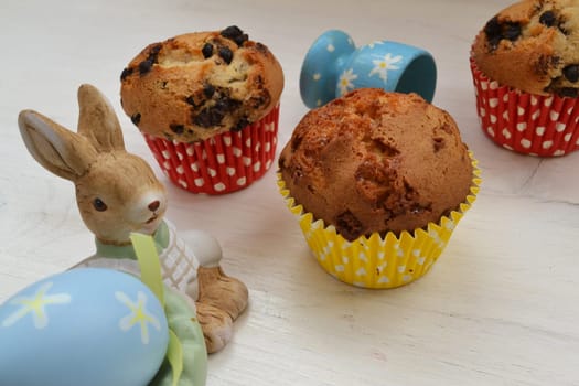 Toy Easter bunny and eggs, muffins on a pastel table