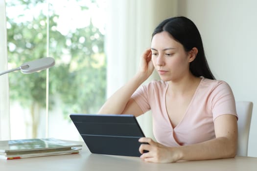 Asian woman using tablet on a desk sitting at home