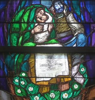God begins salvation in this world through His Son Jesus Christ, detail of stained glass window by Sieger Koder in St. John church in Piflas, Germany