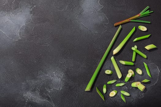 Lemongrass, cut stems atop dark textured backdrop w/ copy space, top view