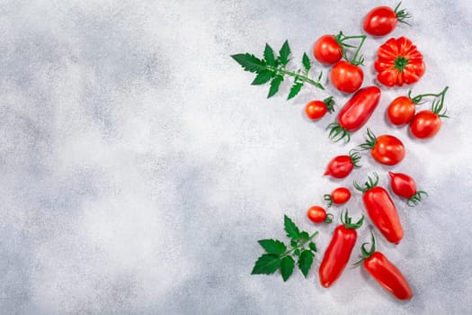 Red heirloom tomatoes on grey textured backdrop, top view