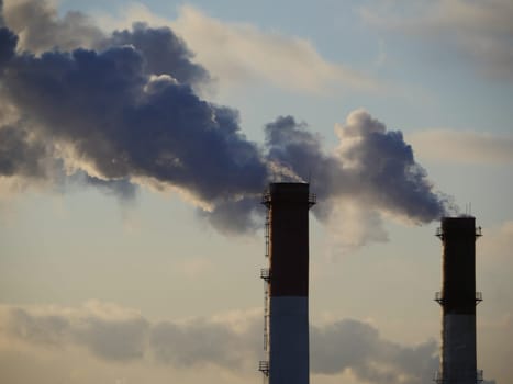 One chimney emits smoke into the blue sky
