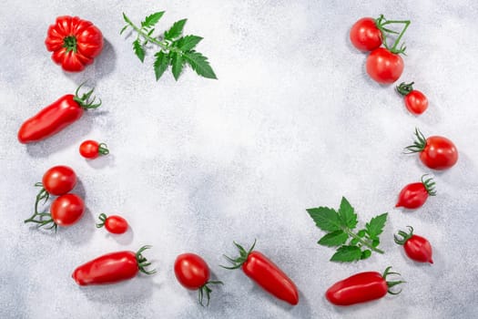 Red heirloom tomatoes on grey textured backdrop, copy space w/ frame, top view