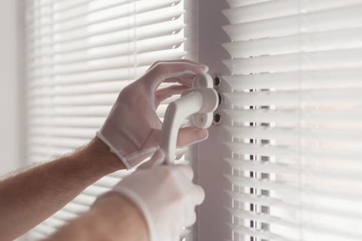 Close-up of hands in gloves with screwdriver, installing a new handle.