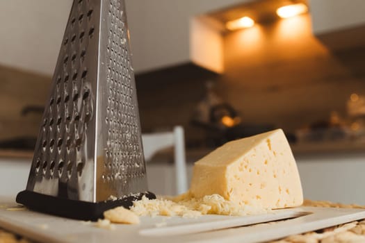 Grater and cheese on kitchen table. Cooking, food and home concept.