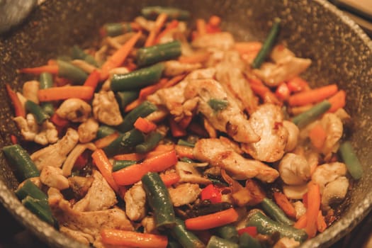 Fried vegetables with turkey meat in a black iron wok pan