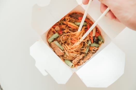 Wok noodles in takeaway box. Wheat noodles with peking duck and vegetables. Traditional chinese cuisine.