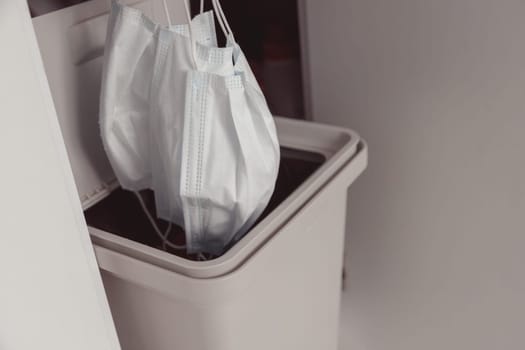 The used face mask is dumped in a trash. Disposal of disposable surgical face masks. Coronavirus quarantine. Mask recycling problem.