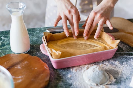 Raw cake batter with halved bananas in ceramic rectangle mould. Banana pie baking