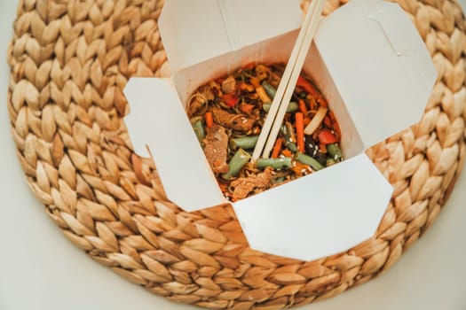 Wok noodles in takeaway box. Wheat noodles with peking duck and vegetables. Traditional chinese cuisine.