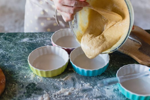 Woman pouring dough from bowl into baking mould for pie