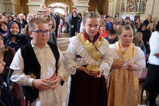 Children dressed in traditional regional folk costumes in the church at the Mass on Thanksgiving day in Stitar, Croatia