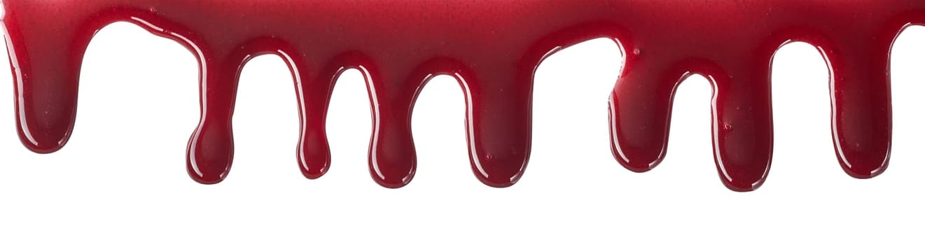 Drips of bloody red cherry or strawberry sweet sauce flowing down on white background viewed in close-up